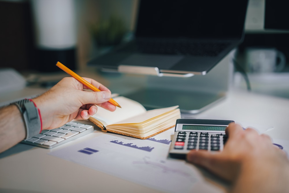 Person reviewing payroll and compliance documents with a calculator